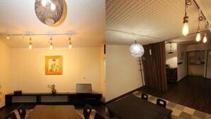 A dining area with a long table and chairs, a painting on the wall, and a ceiling with a grid pattern. - Guesthouse Kyoto Yamashina (Kyoto)
