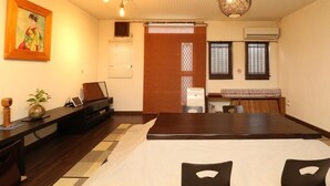 A traditional Japanese-style room with tatami flooring, a low table with a laptop, a piano, and a hanging light fixture. - Guesthouse Kyoto Yamashina (Kyoto)