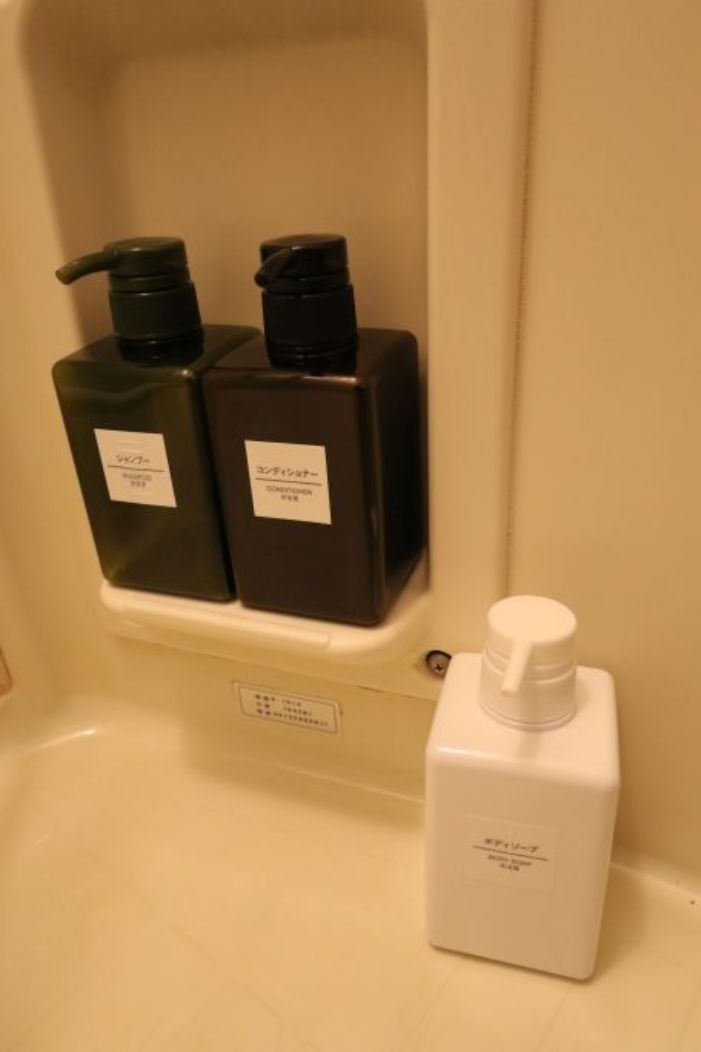 A bathroom with two black bottles labeled in Japanese and a white bottle.