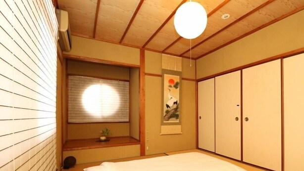 A traditional Japanese-style room with tatami flooring, a futon bed, sliding doors, and a shoji screen. - Guesthouse Kyoto Yamashina (Kyoto)