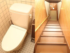 A bathroom with a toilet and a wooden staircase.