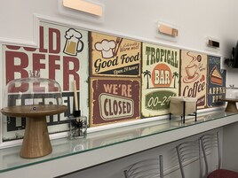 Zona de bar con un expositor de vidrio, una mesa de madera y un cartel que dice 'WE'RE CLOSED'.