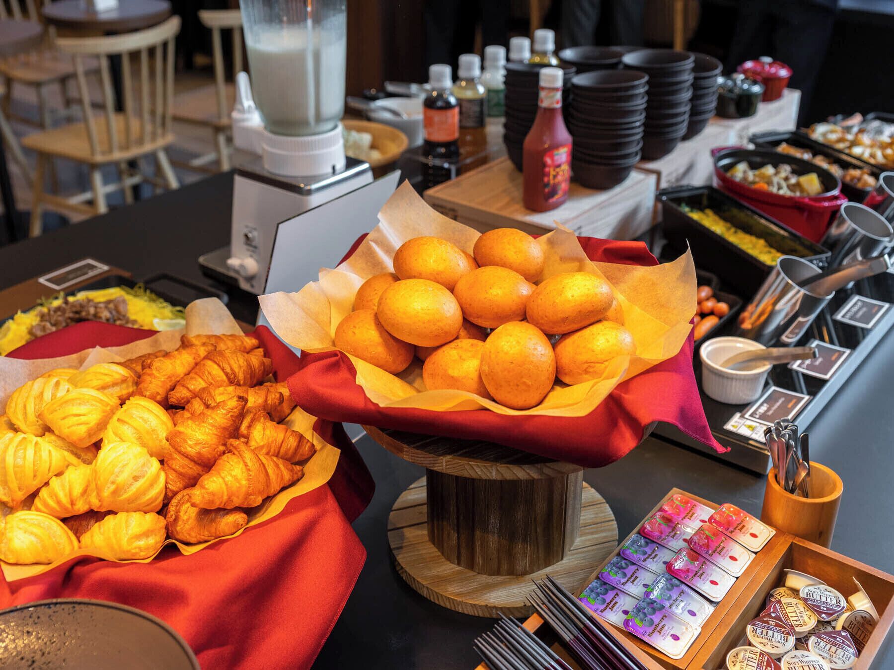 A buffet table with various food items including pastries, oranges, and condiments.