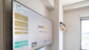 A hotel room with a large screen displaying the hotel's name and amenities. - Super Hotel Premier Shimonoseki (Shimonoseki)