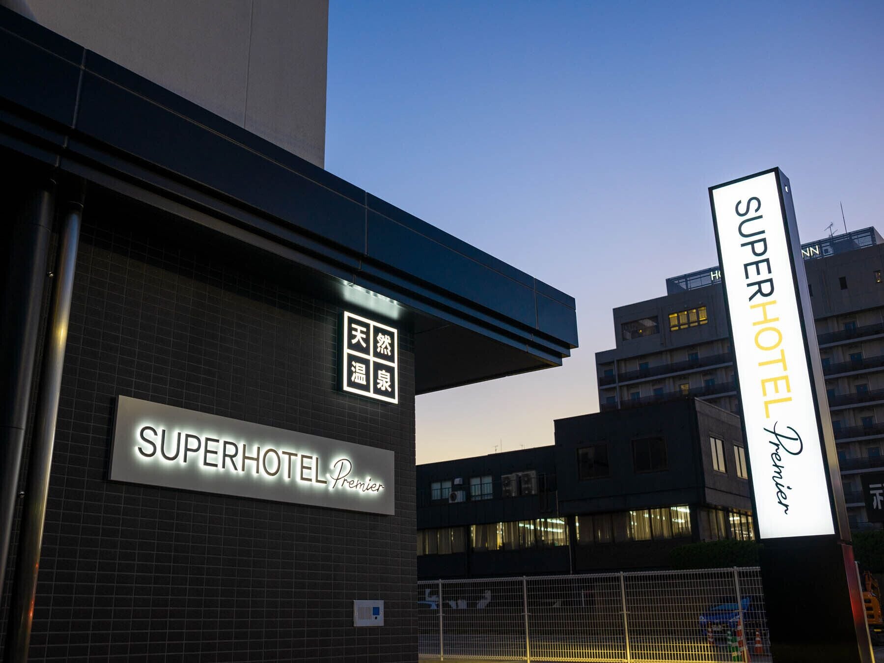 A hotel entrance with a sign reading "Superhotel Premier" and a large vertical sign for "Superhotel Premier".