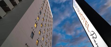 Un hotel con una fachada moderna, múltiples ventanas y un cartel llamativo del Premier Hotel.