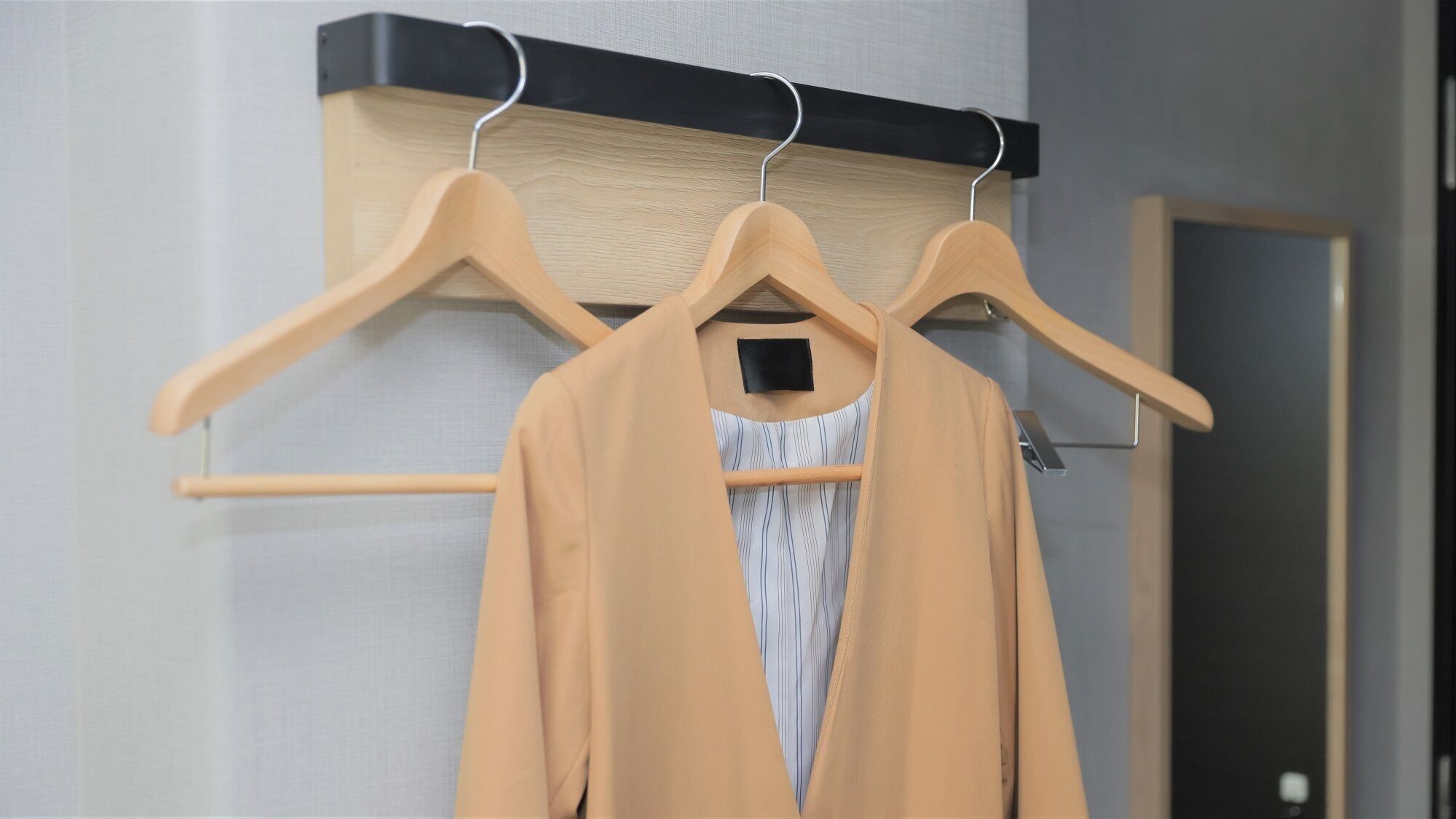 Un perchero con un abrigo color beige y una camiseta a rayas colgadas.
