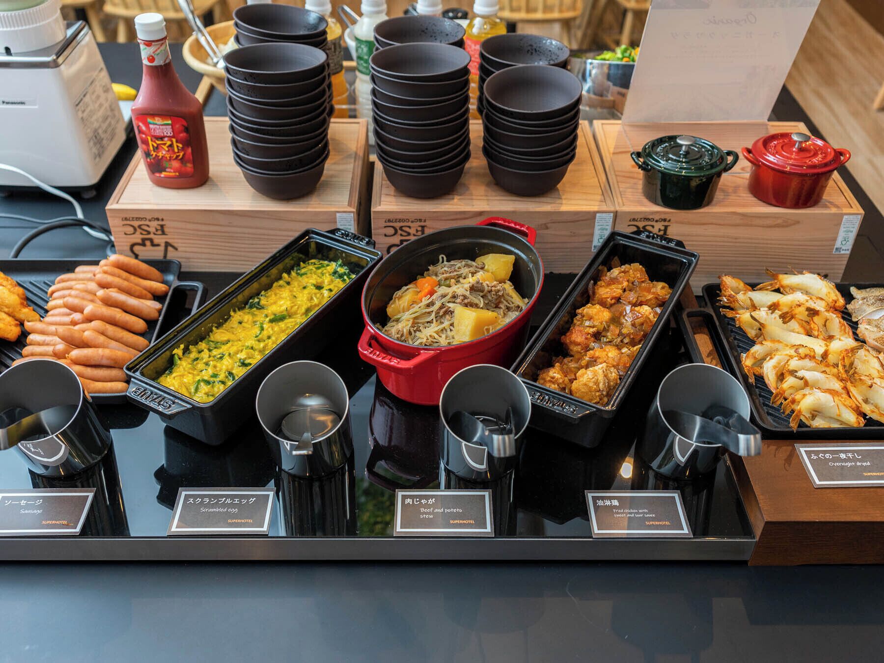Un buffet proposant divers plats, notamment des œufs brouillés, un ragoût de bœuf et des fruits de mer.