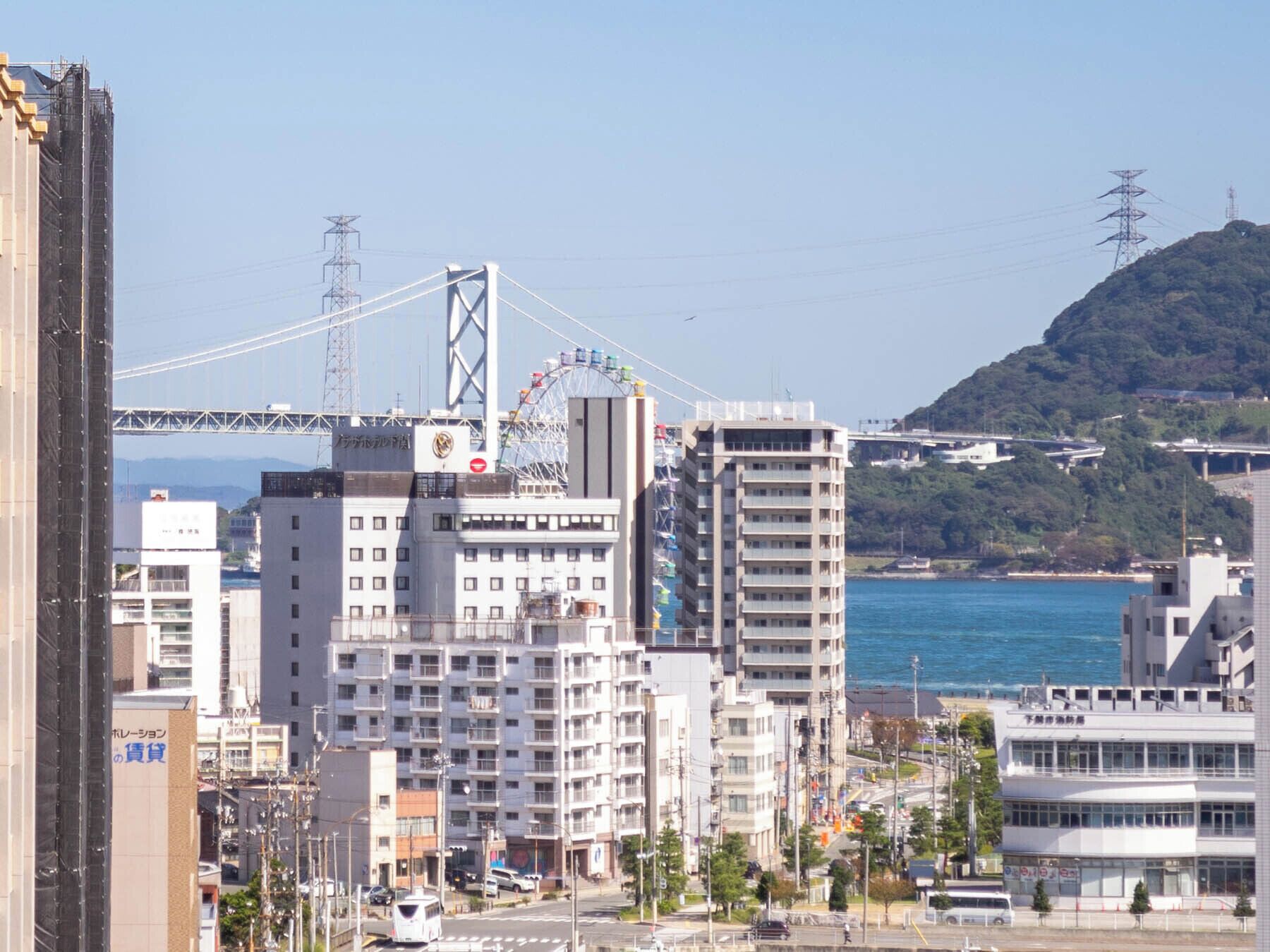A cityscape with modern buildings, a bridge, and a body of water.