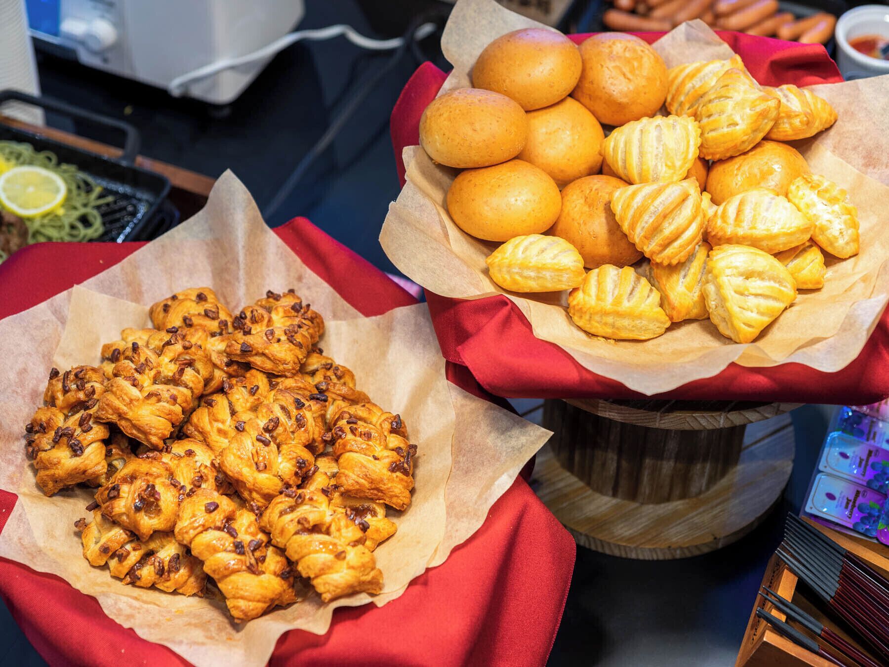 Una mesa de bufé con diversas opciones de panadería, incluyendo pasteles y panecillos.