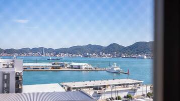A coastal cityscape with a marina, buildings, and mountains in the background.