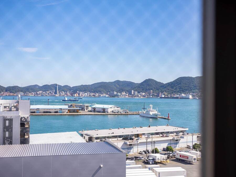 A coastal cityscape with a marina, buildings, and mountains in the background.