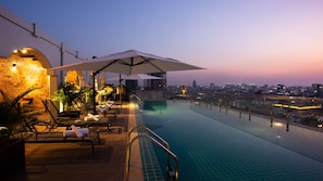 An infinity pool with a city view, lounge chairs, and a bar area. - TK View Hotel Apartment (Phnom Penh)