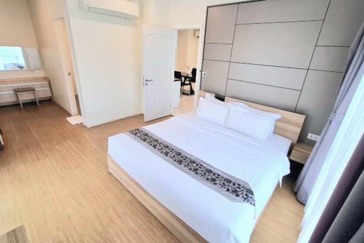 A modern hotel room with a large bed, a desk, and a view of the hallway.