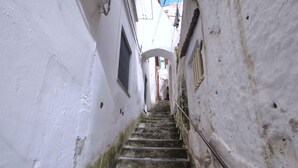 Una escalera de piedra estrecha en un edificio de paredes blancas con barandilla de metal.