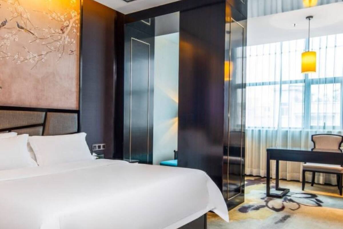 Et moderne hotelværelse med en stor seng, et skrivebord og en stol.