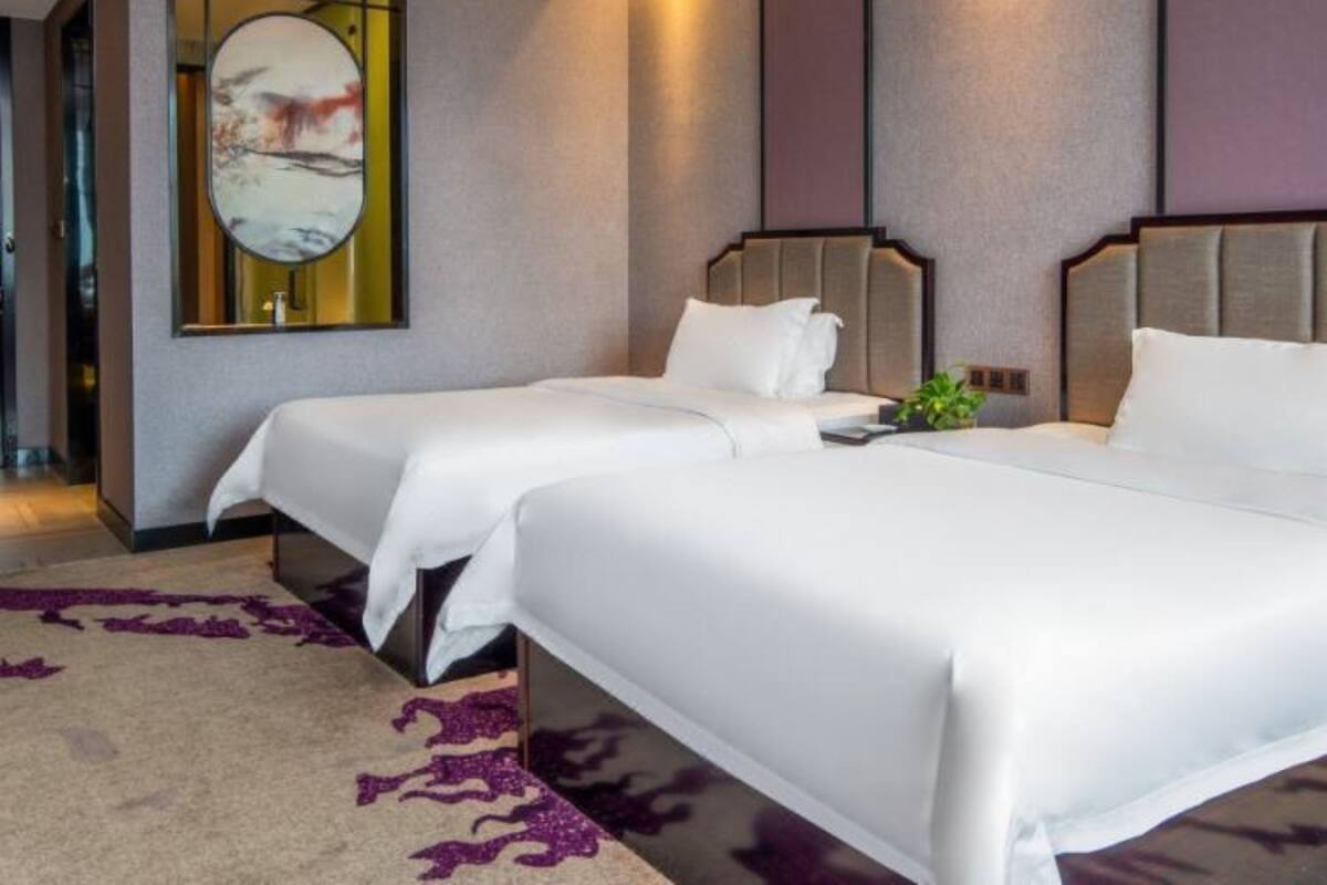 Et hotelværelse med to senge, et stort spejl og et moderne design.