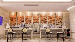 A reception area with marble flooring, a reception desk, and two chairs. - Vyluk J Hotel Wanda Plaza Xiajie Street (Guangzhou)