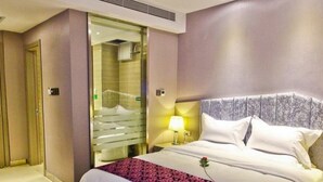 A hotel room with a large bed, a bedside lamp, a bathroom with a glass door, and a carpeted floor. - Urba Hotel · Xi'an North Railway Station (Xi'an)