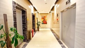 A hotel corridor with marble walls, a large painting, and a potted plant. - Urba Hotel · Xi'an North Railway Station (Xi'an)