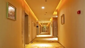 A long, narrow hotel corridor with doors on both sides, a patterned carpet, and overhead lighting. - Urba Hotel · Xi'an North Railway Station (Xi'an)