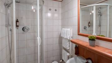 A modern bathroom with a glass-enclosed shower, a white sink, and a mirror.