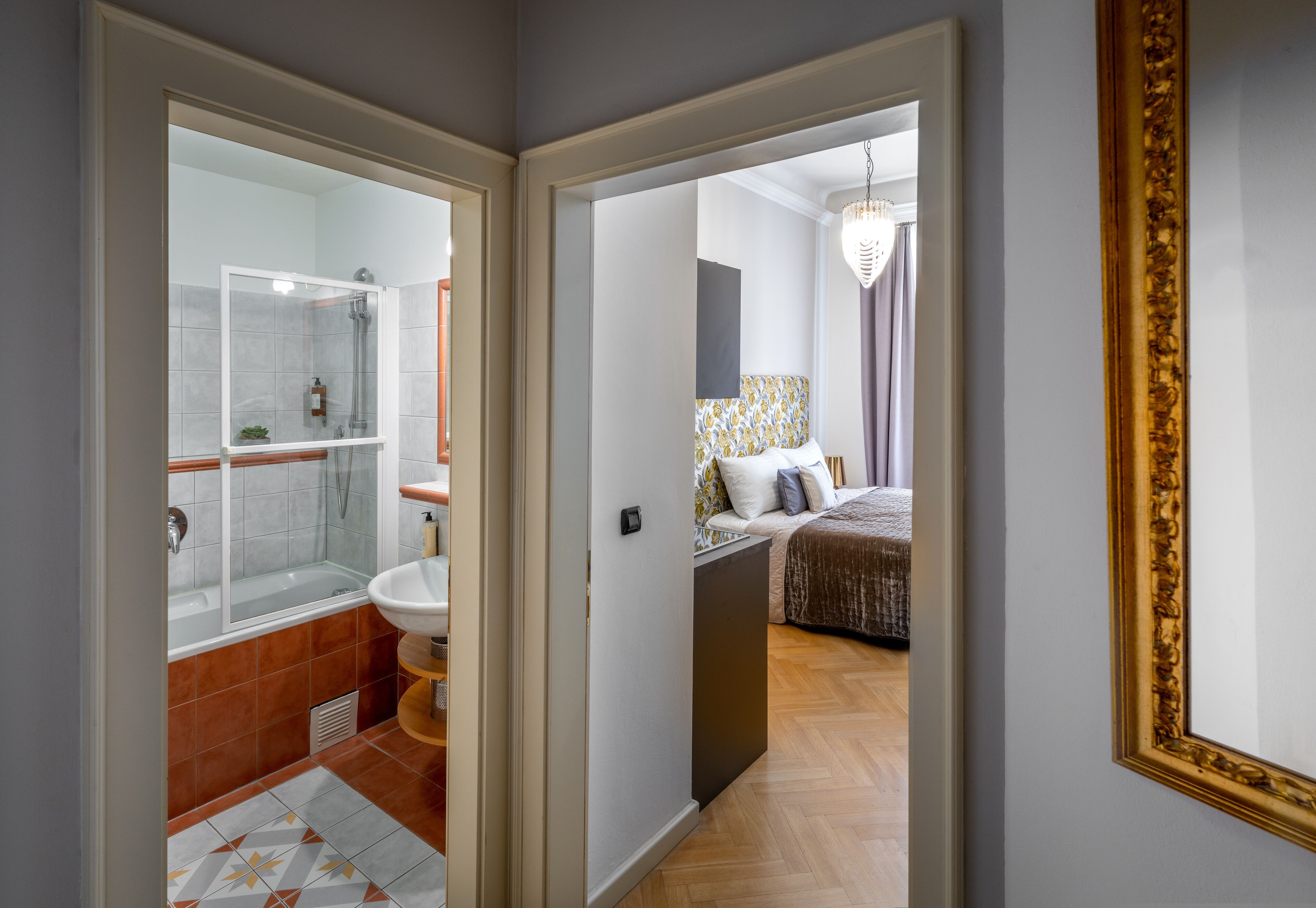Une salle de bain moderne avec une douche à parois de verre, un lavabo et des toilettes. La chambre comprend un lit avec une tête de lit à motifs, une table de chevet et un luminaire suspendu.