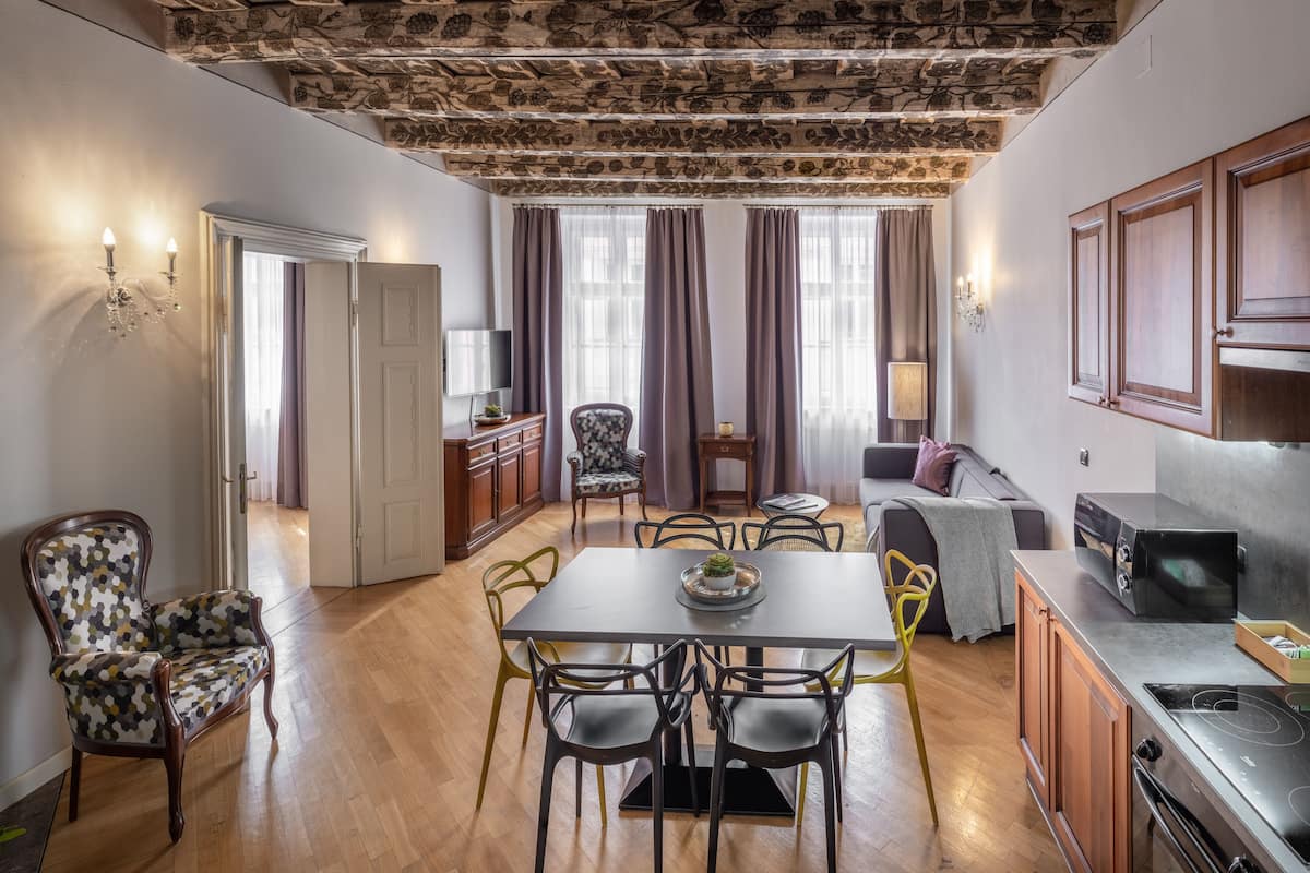 Una cocina moderna con horno y estufa integrados, armarios de madera y una zona de comedor con mesa y sillas.