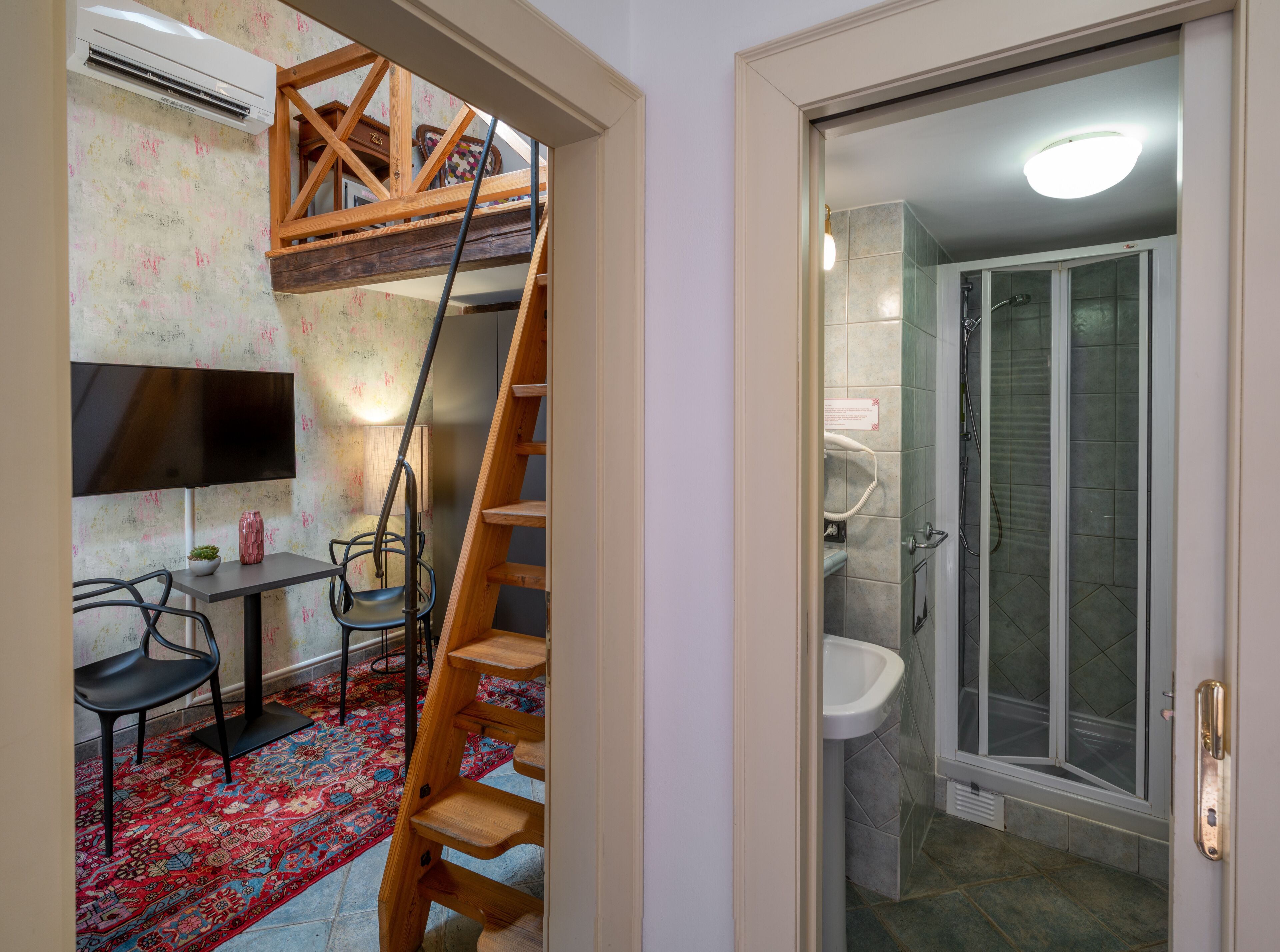 Ett kompakt bostadsutrymme med en träinredd loftvåning, en liten matplats och ett badrum med dusch.