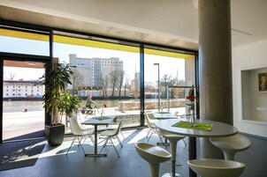 Un comedor interior con amplios ventanales, una planta en maceta y muebles modernos.