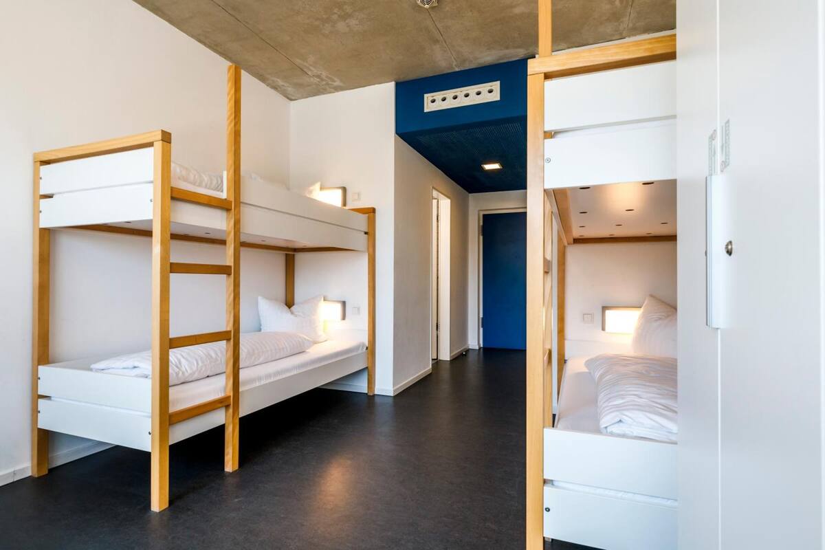A hotel room with bunk beds, a dark floor, and a blue accent wall.