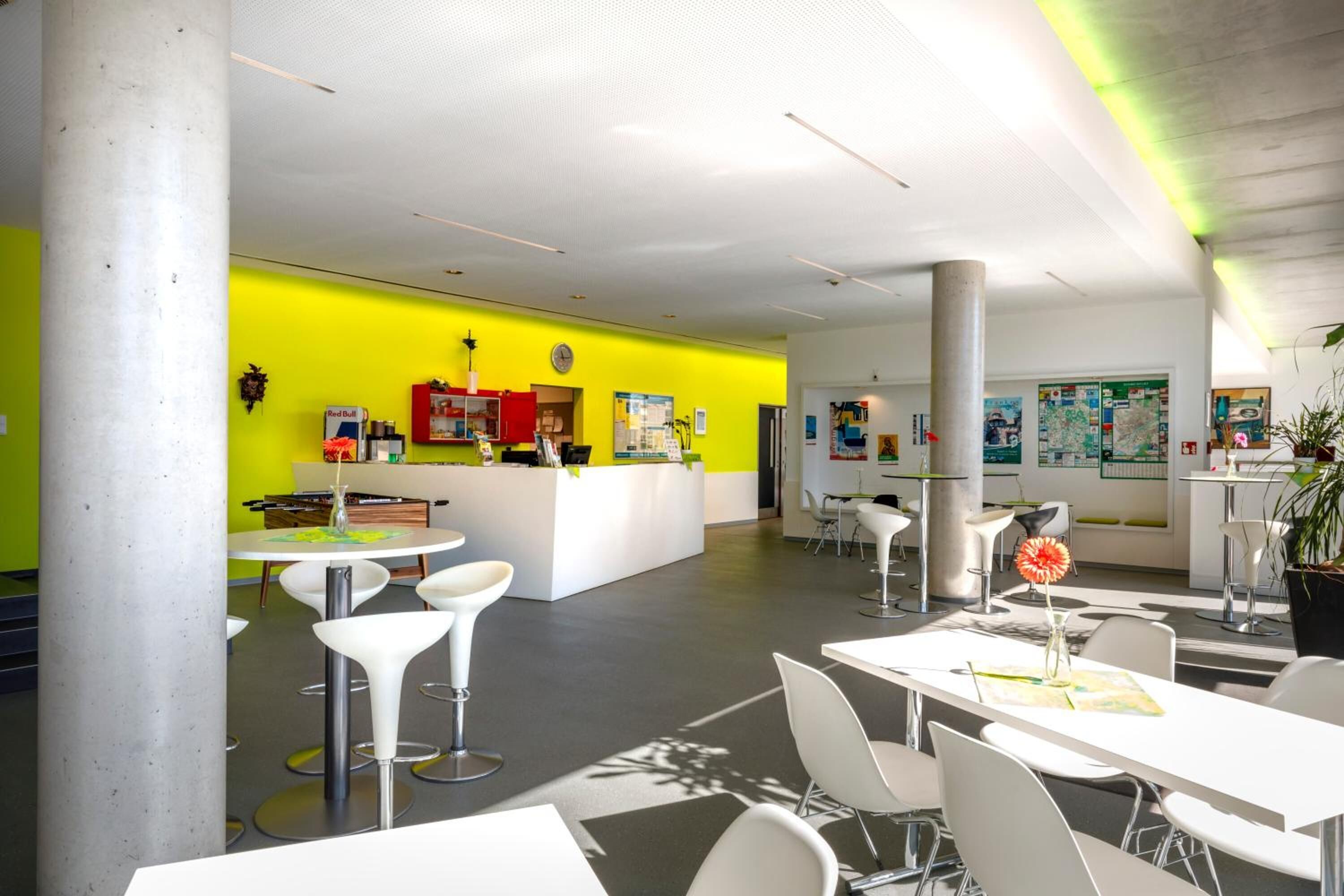 A modern office space with a bright yellow wall, white furniture, and a reception area with a clock and Red Bull branding.