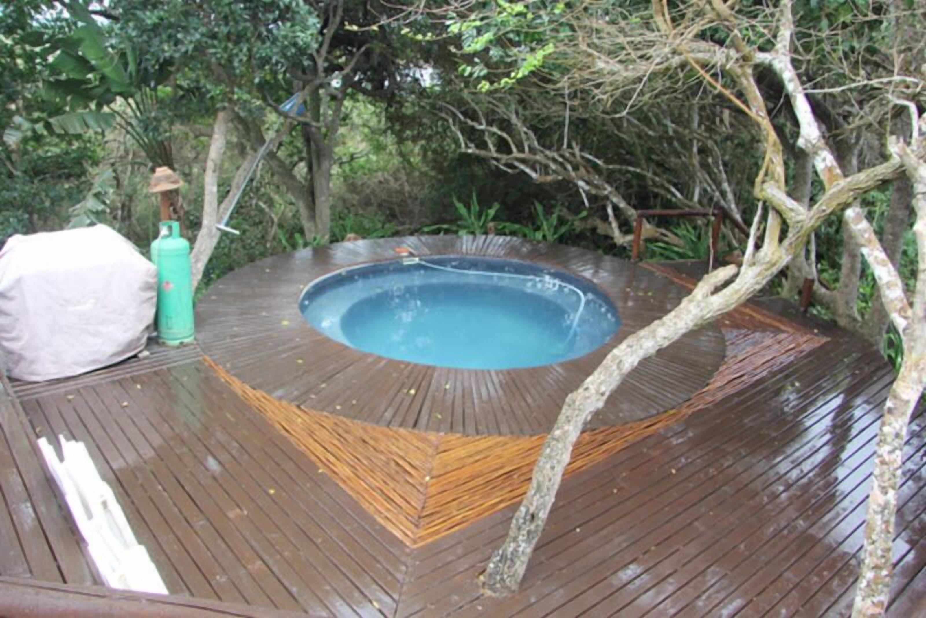 A hot tub on a wooden deck surrounded by trees.