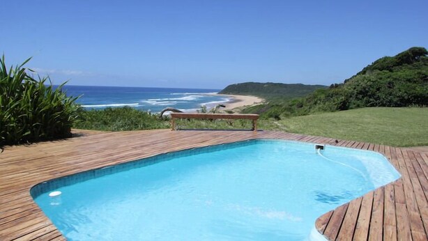 A wooden deck with a swimming pool overlooking a beach. - Kangela 1 (Ponta d'Ouro)