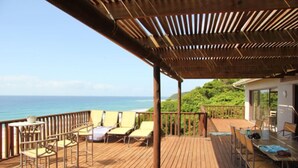 A wooden deck with outdoor seating, overlooking a body of water. - Kangela 1 (Ponta d'Ouro)