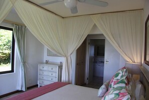 A bedroom with a bed, a dresser, and a ceiling fan. - Kangela 1 (Ponta d'Ouro)
