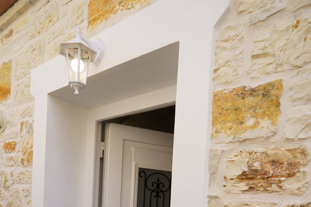 A white door with a nameplate reading "IOANNA" and a small step leading to the entrance.