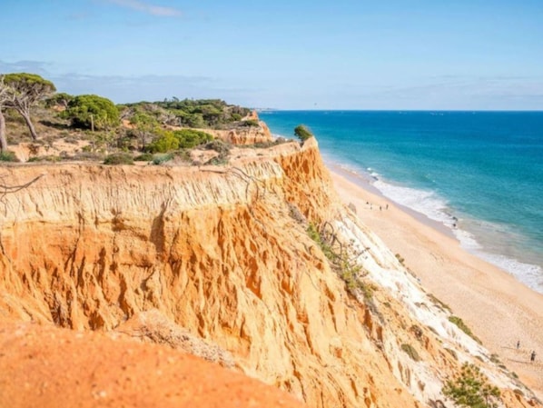 Overlooking a serene beach, this property offers stunning views of the ocean and layered rock formations.