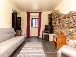 Ein gemütliches Wohnzimmer mit Steinwand, einer Couch, einem Kamin und einem Fenster mit Vorhängen.