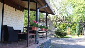 An outdoor patio with wicker furniture, potted plants, and a stone wall.