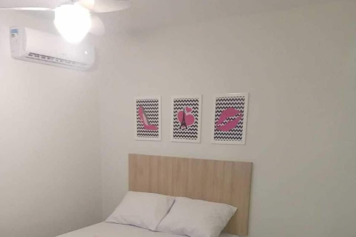 A bedroom with a bed, a chair, and three wall art pieces.