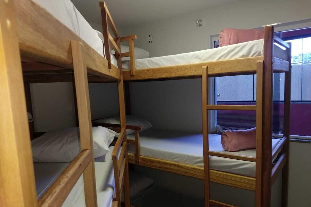 A bunk bed room with wooden frames and white bedding.