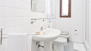 Een badkamer met witte tegels, een wastafel, toilet en spiegel.