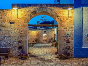 Une entrée en arc de cercle, faite de pierres, mène à un bâtiment au-dessus de laquelle on peut voir une enseigne.