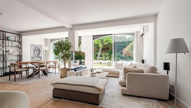 Un salón amplio con un gran ventanal, un sofá, una mesa de centro y una estantería.
