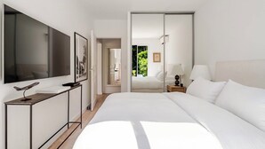 Habitación de hotel moderna con una cama grande, un escritorio, un televisor y una puerta corrediza que da a un balcón.