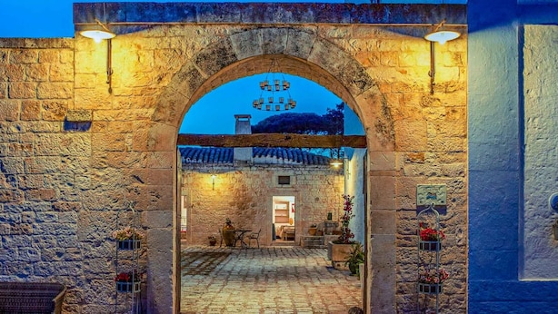 An arched stone entrance to a building with a sign above it.