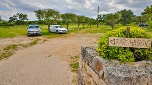 Une route de campagne bordée de voitures garées et d’un panneau indiquant « PARCHEGGIO ».