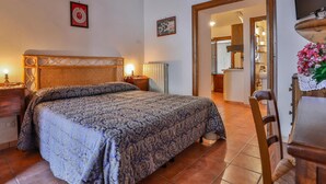 Une chambre à coucher avec une tête de lit en bois, une couvre-lit à motifs, une table de chevet avec une lampe et une chaise en bois.