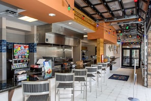 A modern restaurant with a bar area, seating, and a kitchen visible through the glass wall. - Tropical Luxury Near Disney! Professionally Decorated With Huge Pool, Game Room. 6bd/ 4.5ba #6st129 (Davenport)